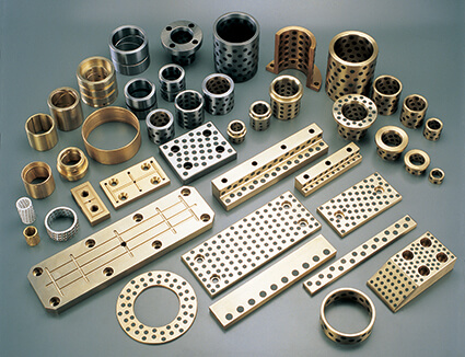 JBM-650 graphite plugged bronze bushing — golden brass body with embedded black graphite plugs in staggered geometric pattern, Oiles 500SP equivalent